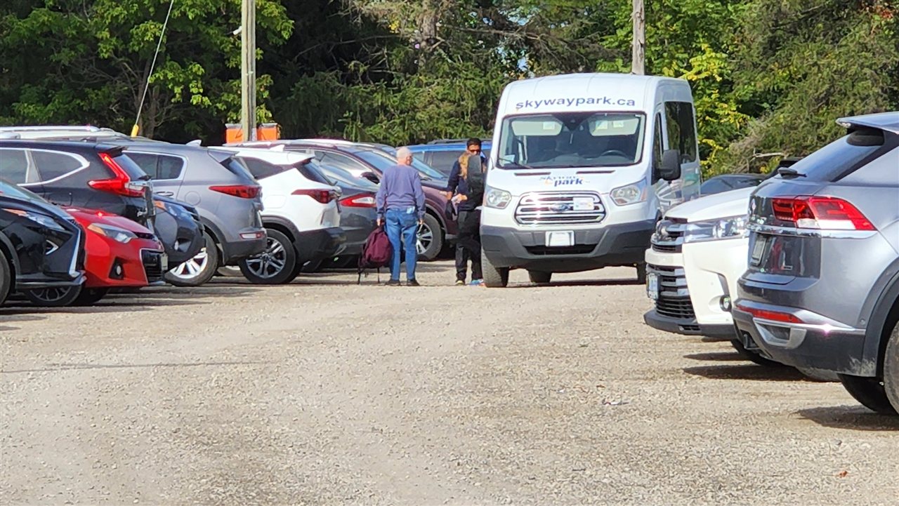 Skyway Park shuttle beside parked cars